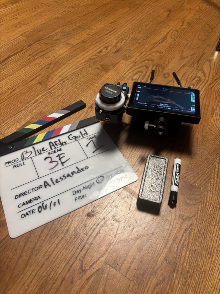 Blue After Gold film slate beside a wireless production monitor and focus-pulling equipment on a wooden floor.