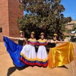 Four dancers pose outdoors during Latin Fest, with two wearing colorful traditional Venezuelan attire.