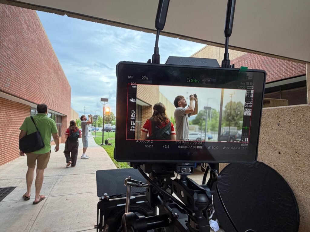 Film camera and production monitor in the foreground as the Blue After Gold crew works on an outdoor scene.