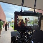 Film camera and production monitor in the foreground as the Blue After Gold crew works on an outdoor scene.