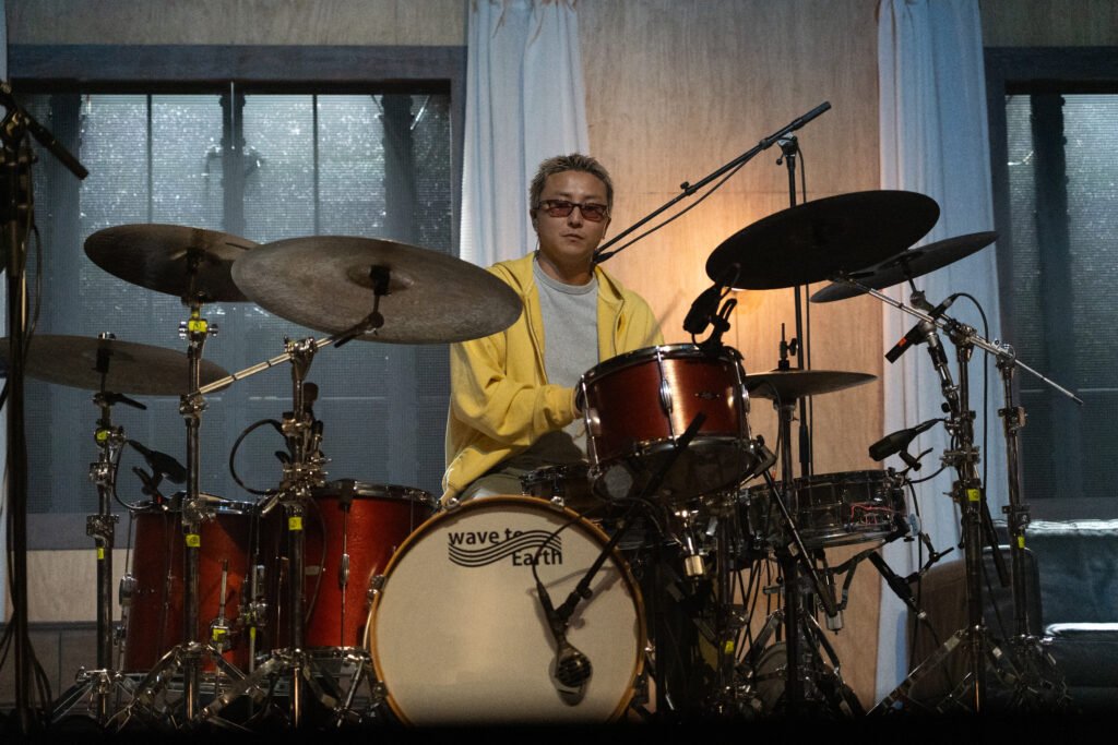 wave to earth’s drummer performs behind a red drum kit on the house-inspired stage.