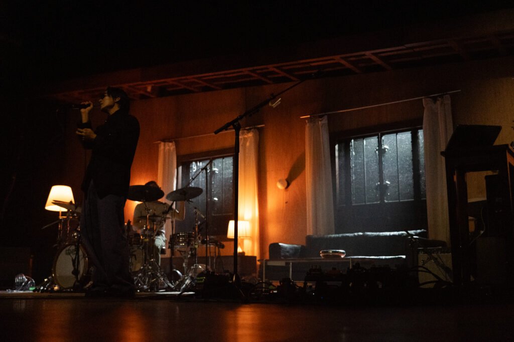 Warm orange stage lighting fills wave to earth’s house-inspired set as the band performs.